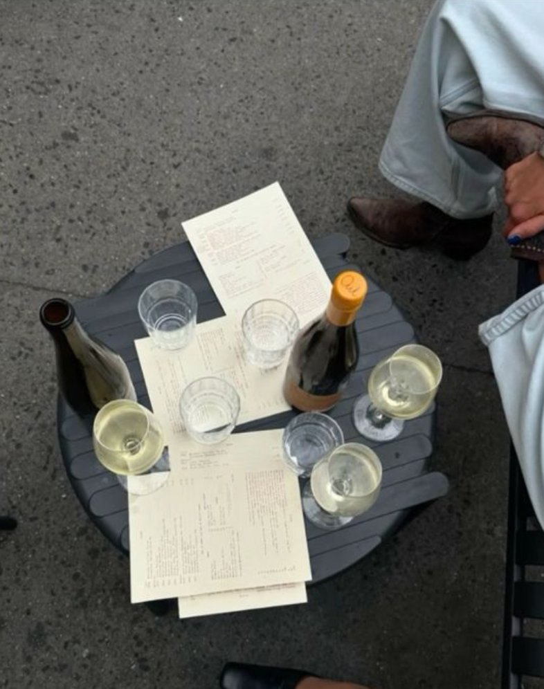 Wijnglazen en wijnkaarten op een tafel buiten bij een horecazaak